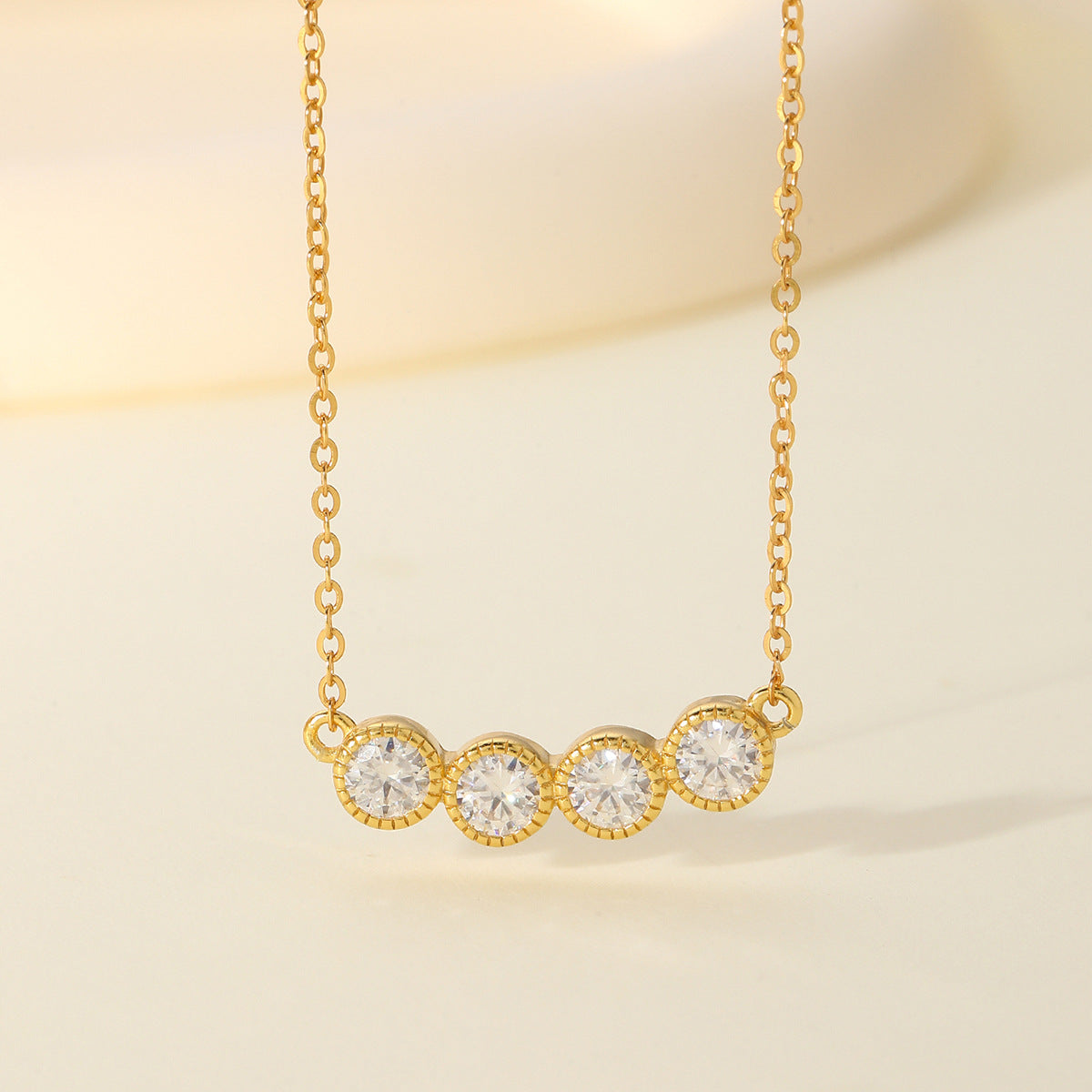 Gold necklace with three clear gemstones on a beige background