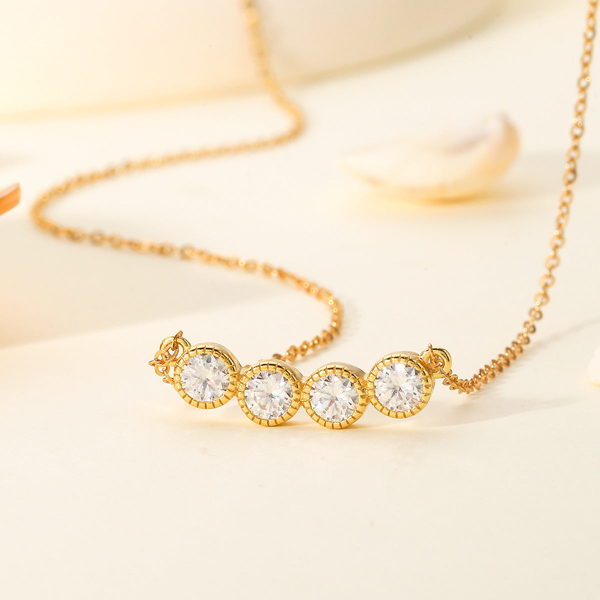 Gold necklace with three clear gemstones on a light background