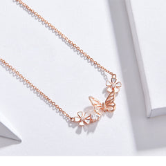 Rose gold butterfly necklace on a white background