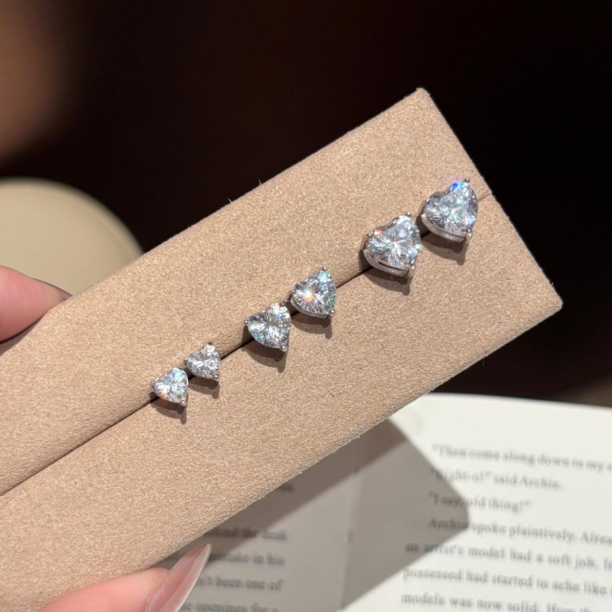 Heart-shaped diamond earrings on a brown card