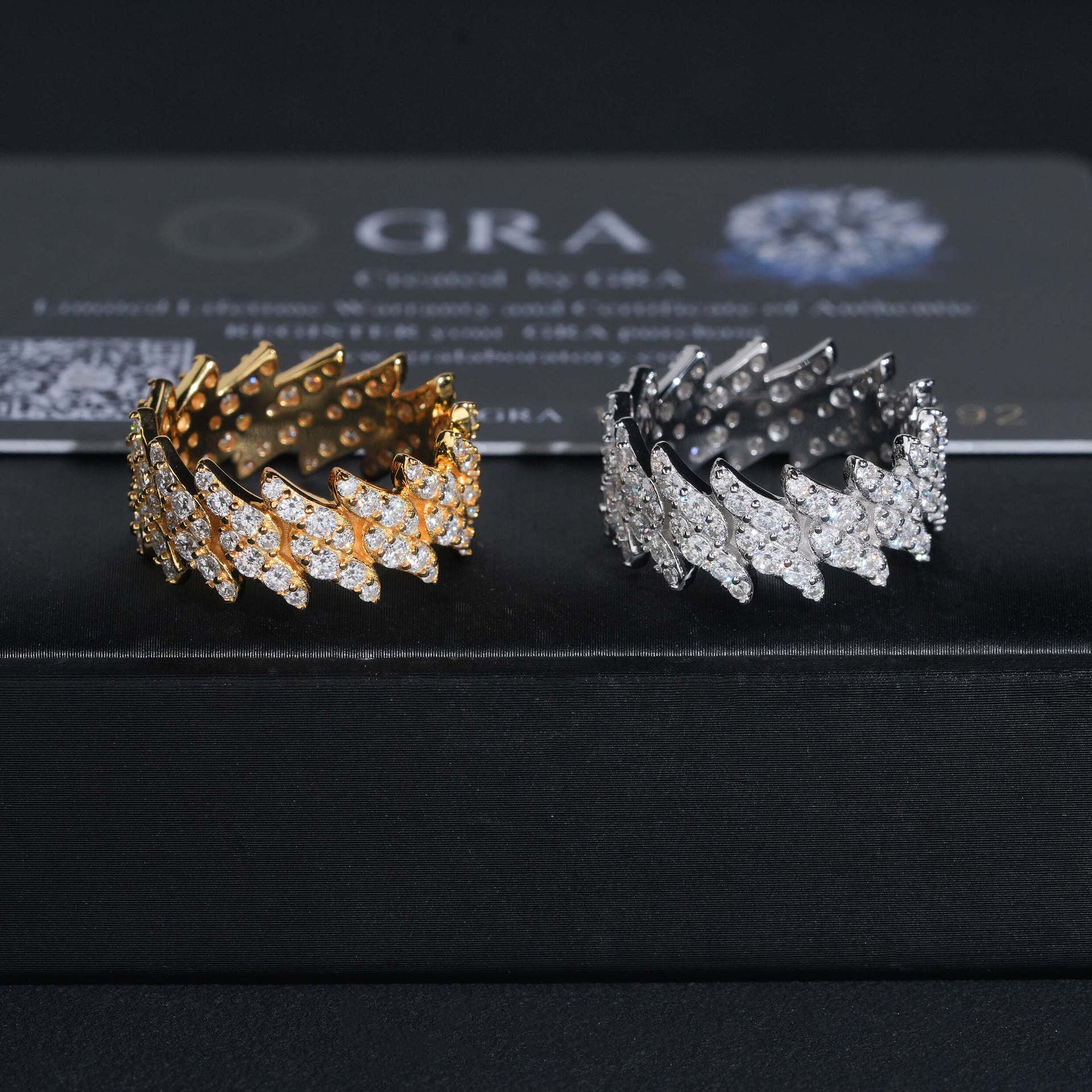 Two gold and silver bracelets on a black surface with 'GRA' branding in the background.