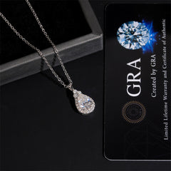 Teardrop-shaped diamond necklace next to a GRA card on a dark surface