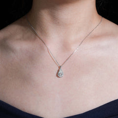 Necklace with a teardrop-shaped pendant on a person wearing a dark top.