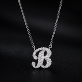 Silver necklace with a 'B' pendant on a dark background