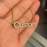 Custom name necklace with gold plating held in hand