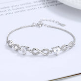 Silver bracelet with heart-shaped crystals on a white surface Silver bracelet with infinity symbols Aru Collection