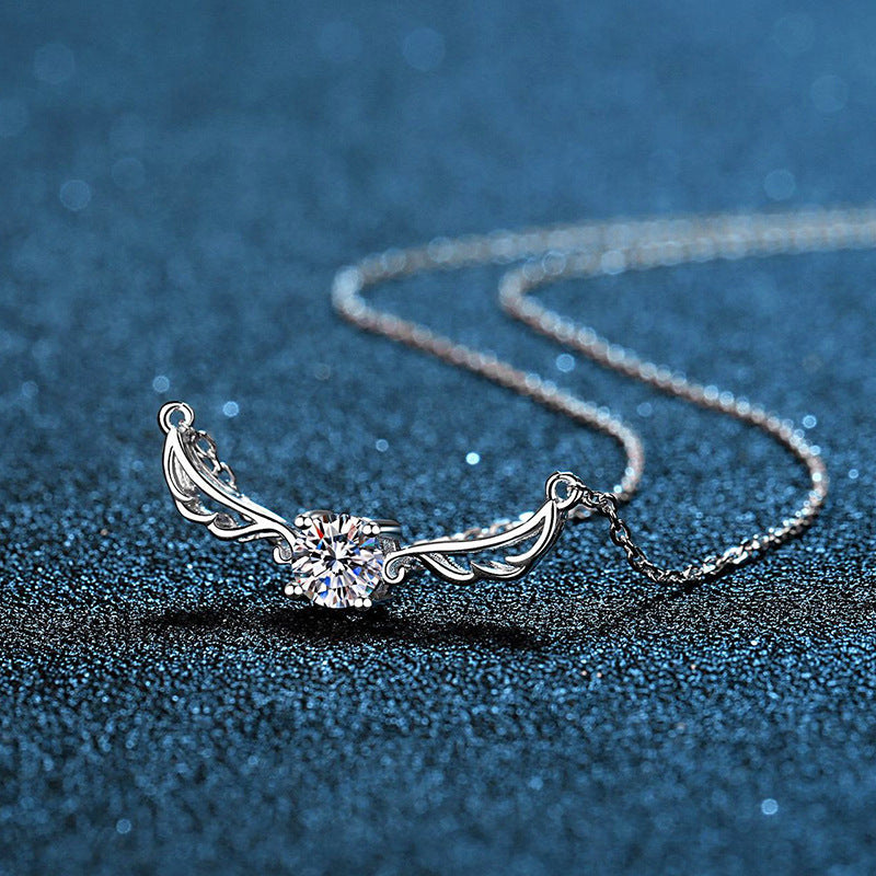 Silver necklace with a heart-shaped pendant on a blue textured background angel wing design Silver necklace Aru collection