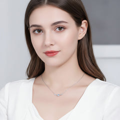 Silver necklace with a blue gemstone worn by a person in a white top. angel wing design Silver necklace Aru collection
