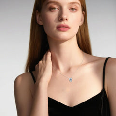 Woman wearing a necklace with a blue pendant against a neutral background