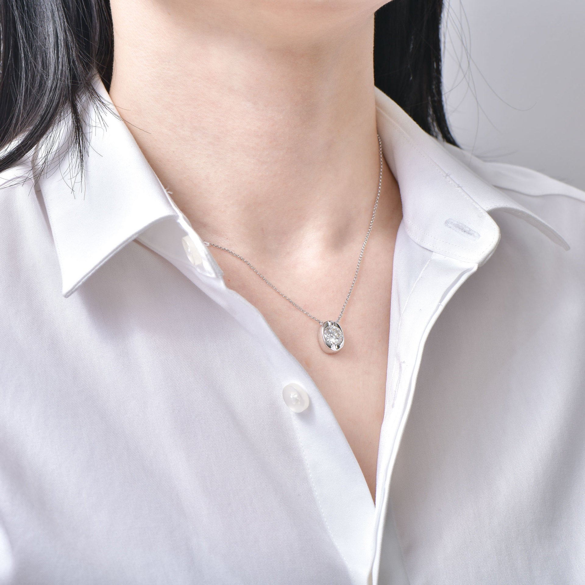 Necklace with a pendant worn by a person in a white shirt