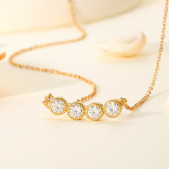 Gold necklace with three clear gemstones on a light background