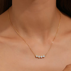 Gold necklace with three small diamonds on a person's neck