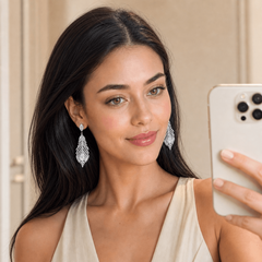 Woman wearing silver feather stud earrings, neutral background