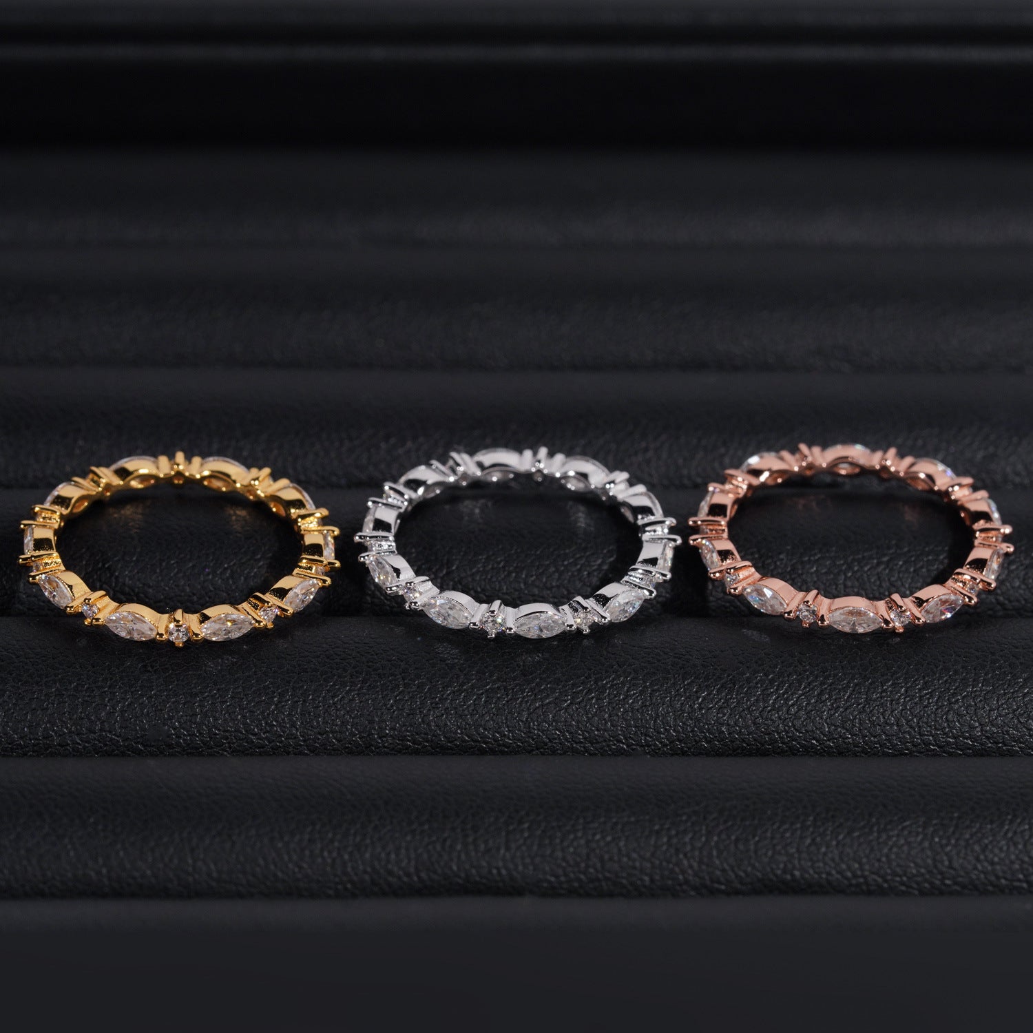 Three rings in gold, silver, and rose gold on a black background