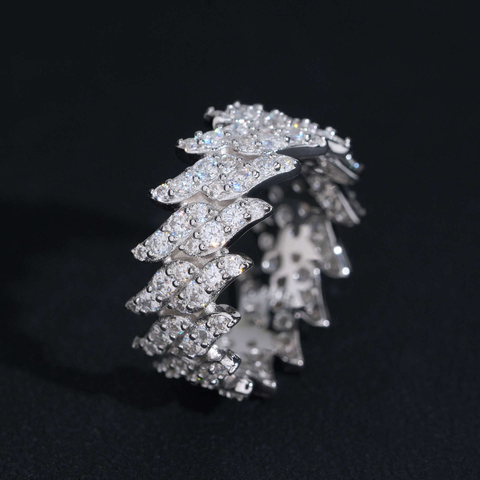 Silver ring with multiple layers of diamonds on a black background
