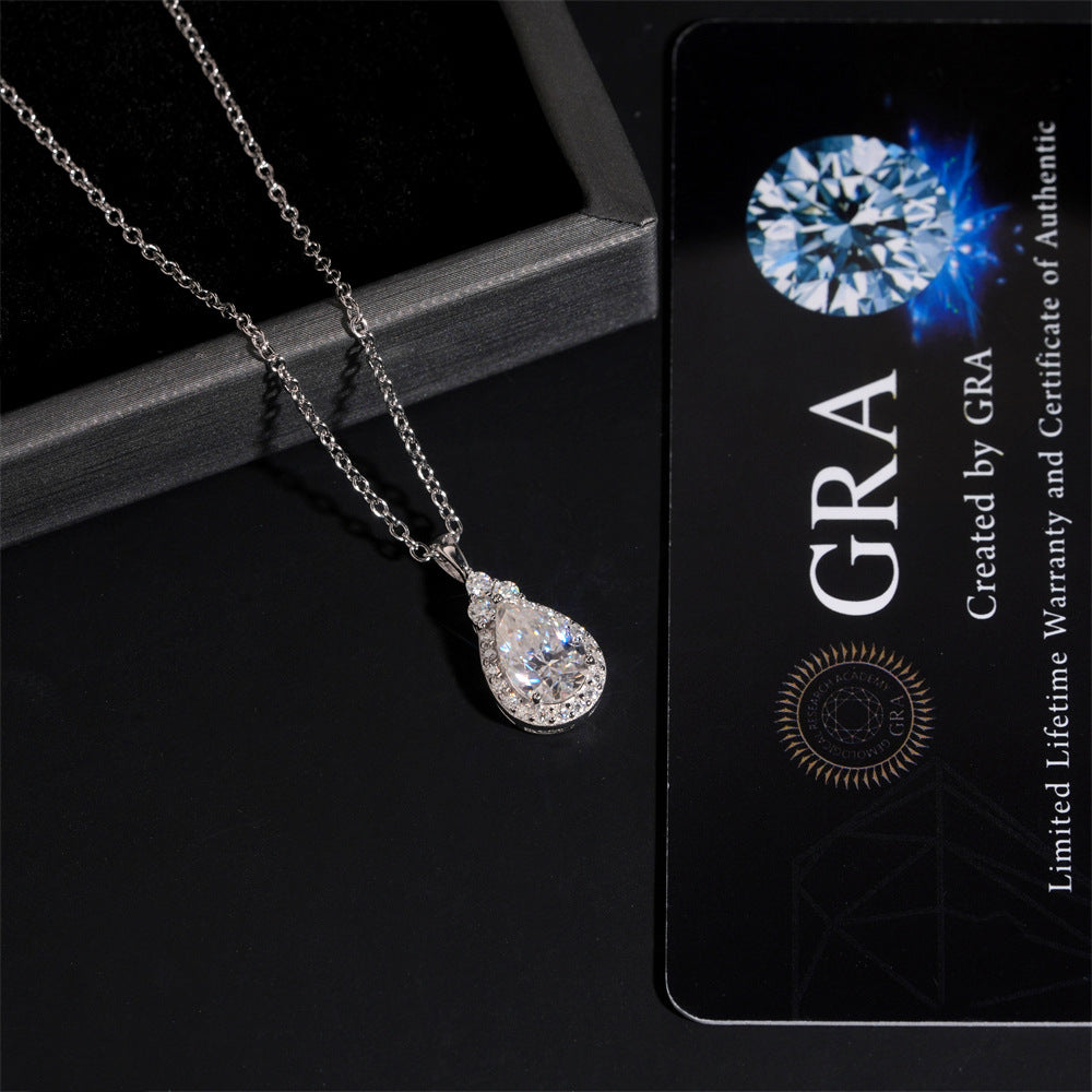 Teardrop-shaped diamond necklace next to a GRA card on a dark surface