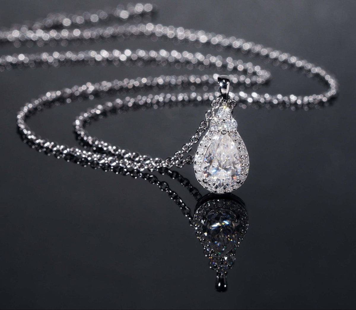 Silver necklace with a teardrop-shaped pendant on a dark background, featuring the brand 'Zuanfa'.