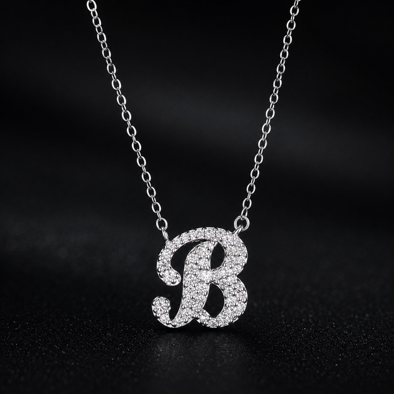 Silver necklace with a 'B' pendant on a dark background