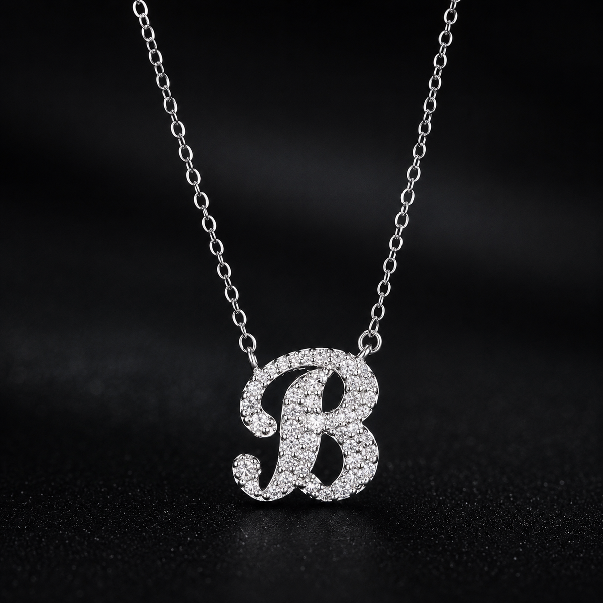 Silver necklace with a 'B' pendant on a dark background