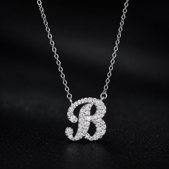 Silver necklace with a 'B' pendant on a dark background