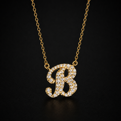 Gold necklace with a diamond-studded letter 'B' pendant on a black background