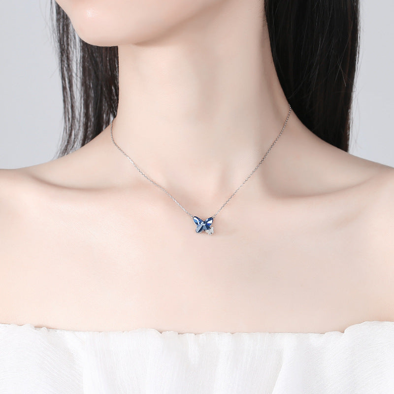 Necklace with a blue butterfly pendant on a plain background