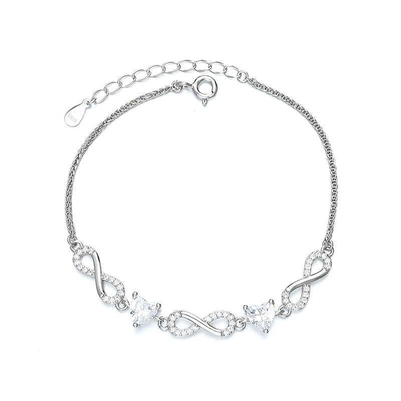 Silver bracelet with infinity symbols and clear stones on a white  Aru Collection background