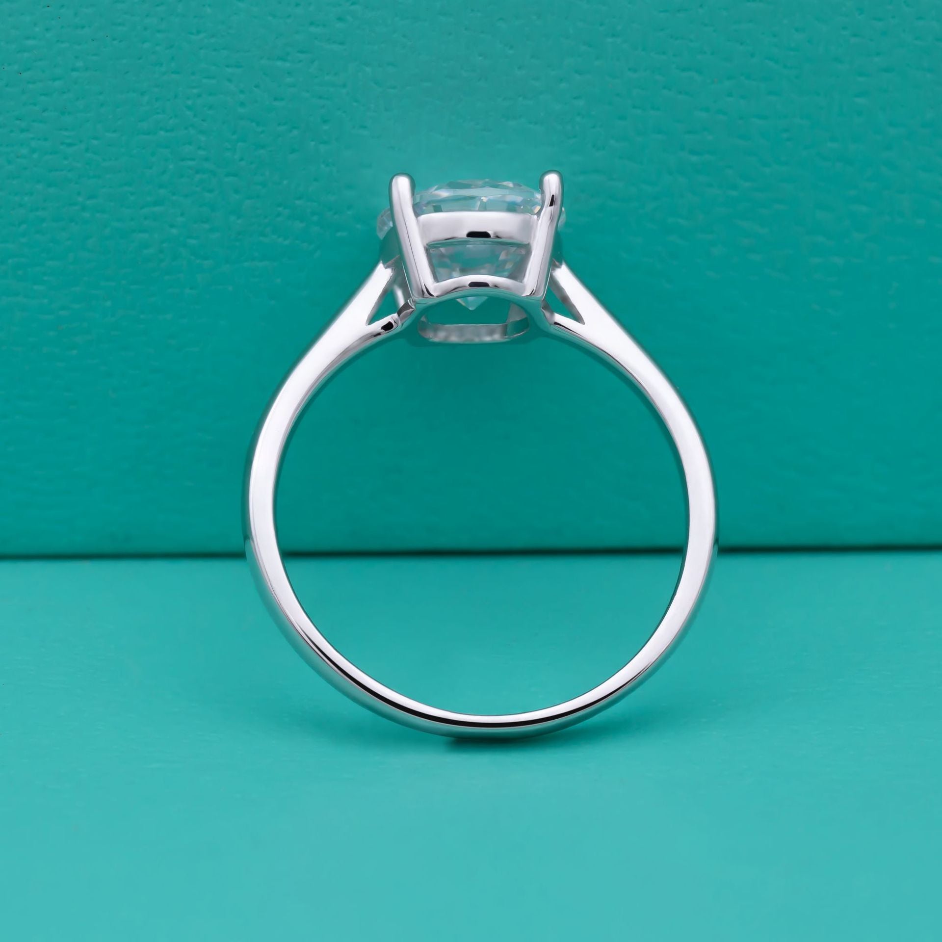 Silver ring with a diamond on a teal background