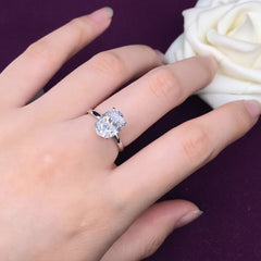 Silver ring with a large diamond on a hand against a black background