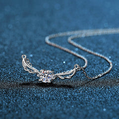 Silver necklace with a heart-shaped pendant on a blue textured background angel wing design Silver necklace Aru collection 
