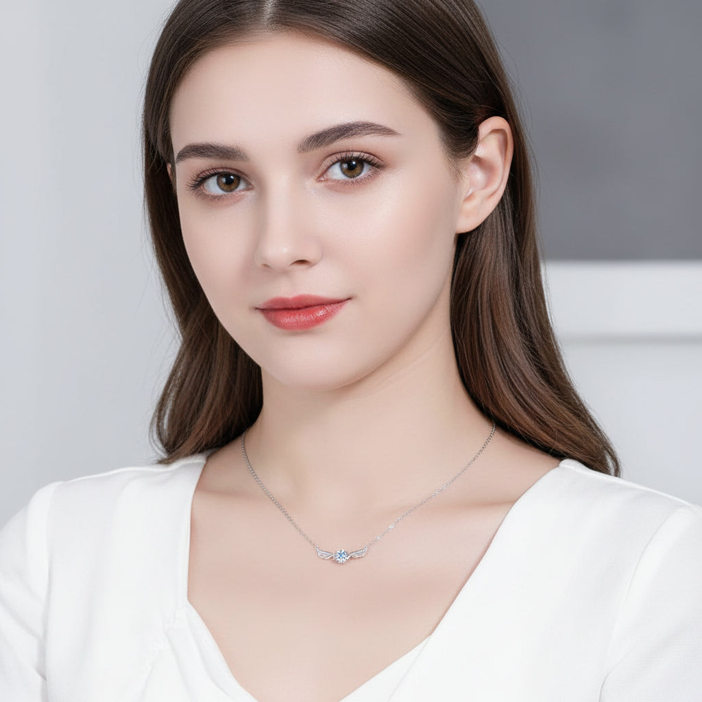 Silver necklace with a blue gemstone worn by a person in a white top. angel wing design Silver necklace Aru collection 